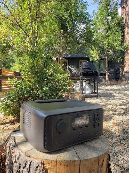 EcoFlow RIVER 3 portable power station placed outside at a cabin campsite