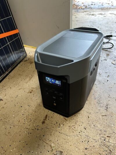 EcoFlow Delta 2 Max charging setup near a solar panel in a garage with the front display powered on