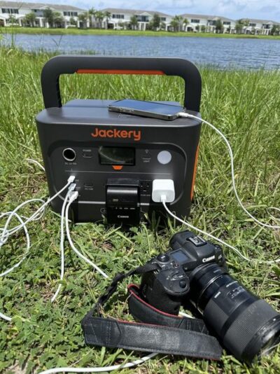 Jackery Explorer 1000 charging camera gear and a phone during outdoor use near a lake