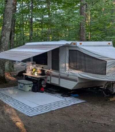 Pop-up camper campsite in the woods using portable power for off-grid camping comfort
