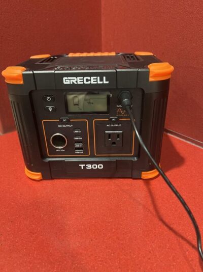 GRECELL T300 portable power station recharging from a wall outlet with battery display visible