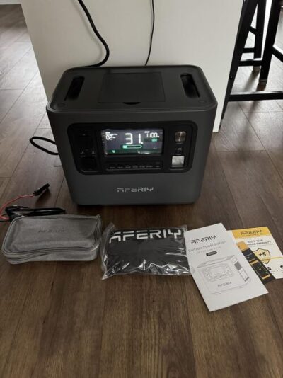 AFERIY P210 portable power station charging indoors with cable pouch, dust cover, manual, and warranty card