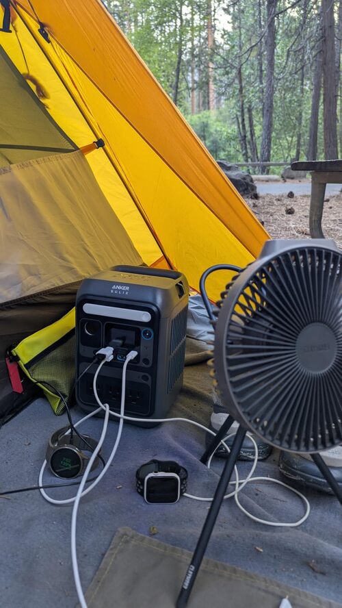Anker SOLIX portable power station charging devices inside a yellow camping tent