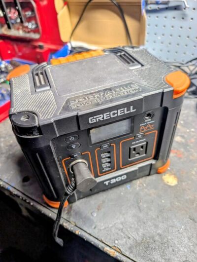 GRECELL T300 portable power station powering a 12V device on a workbench