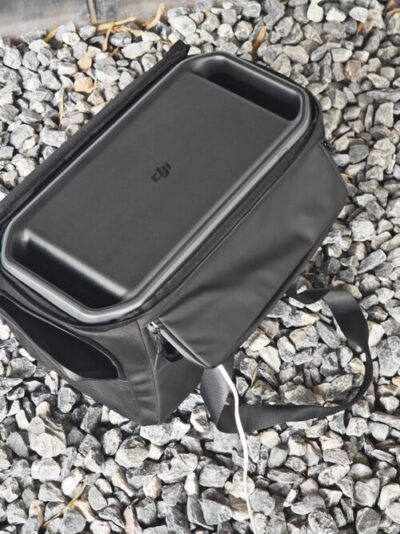 DJI Power 1000 V2 stored in a protective carrying case on gravel with a charging cable connected