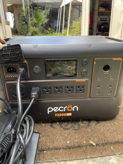 Close-up of Pecron F3000LFP solar generator connected outdoors with AC input and multiple output ports visible