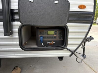 Pecron F3000LFP portable power station installed in an RV storage compartment and connected to camper power