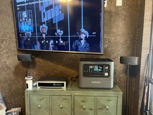 AFERIY P210 powering a TV, router, and speaker setup as indoor backup power for home entertainment