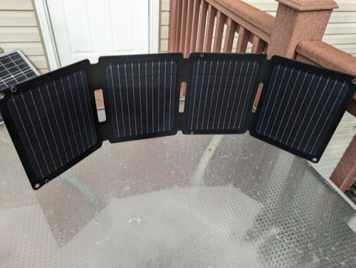 Anker SOLIX PS30 30W solar panel fully unfolded into four monocrystalline sections on a glass patio table
