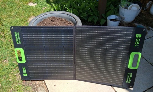 EBL 200W foldable solar panel set up open on a backyard patio beside a garden in direct sun