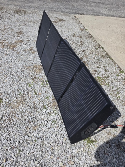 ECO-WORTHY 200W portable solar panel deployed flat on a gravel driveway outdoors with its MC4 leads attached