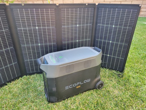 EcoFlow 220W bifacial solar panel charging an EcoFlow Delta power station on a grass lawn in full sun
