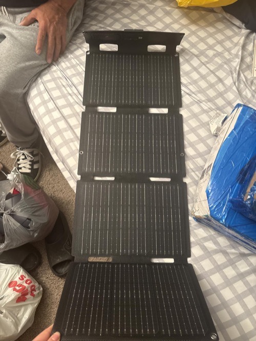 EcoFlow 45W four-panel solar panel unfolded full length on a bed indoors, showing its compact size for scale