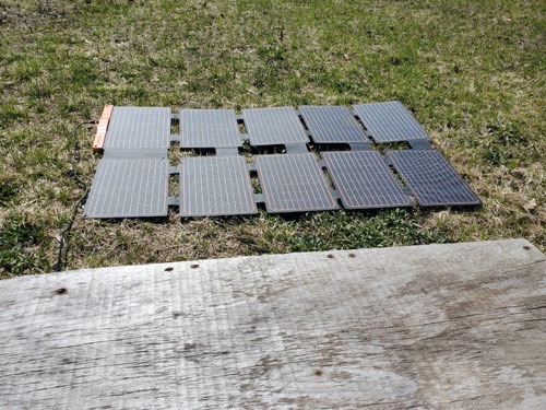 FlexSolar lx-S100 100W portable solar panel unfolded flat on grass showing its ten-cell foldable array