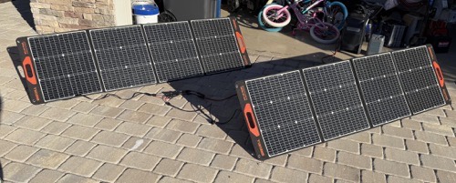 Two GRECELL SP-100 100W folding solar panels deployed side by side on a paver driveway and connected together