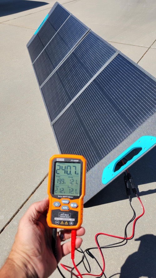 Renogy RPP200EF-SE solar panel set up on a driveway with a handheld MPPT meter showing live wattage output in full sun