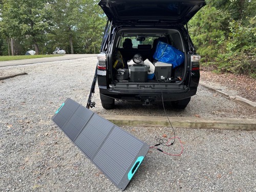 Renogy RPP200EF-SE 200W solar panel deployed beside an SUV loaded with camping gear at a campsite
