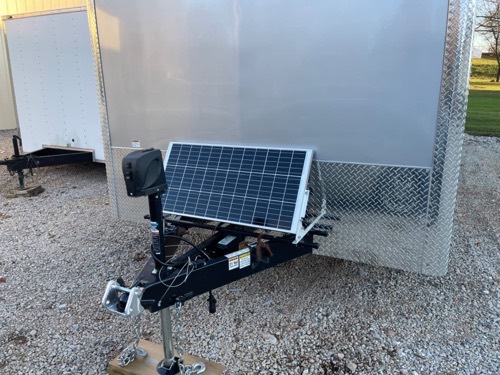 Topsolar 100W solar panel mounted on the tongue of an enclosed cargo trailer to maintain its 12V battery