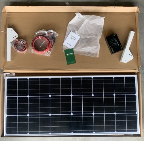 Topsolar 100W solar panel kit unboxed with monocrystalline panel, PWM controller, MC4 and O-ring cables, brackets, and manual laid out in the box