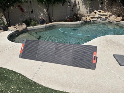 TWELSEAVAN 200W portable solar panel unfolded flat on a concrete patio beside a backyard pool