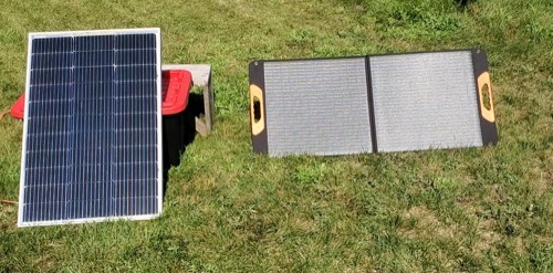 ZOUPW 100W foldable solar panel laid flat on grass next to a rigid framed 100W solar panel for size comparison