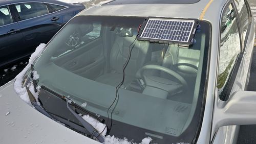 Customer photograph of a POWOXI 7.5W panel resting against a parked car windshield