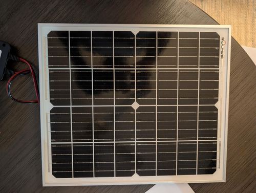 SOLPERK owner photograph of a framed 20W panel with part of its controller lead visible